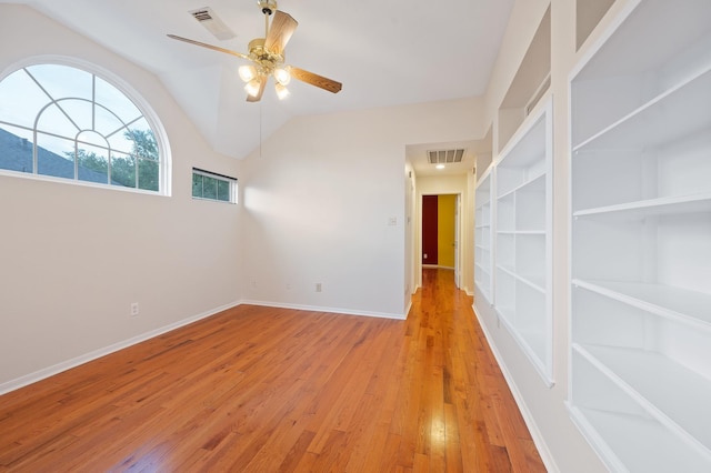 spare room featuring ceiling fan, light wood-type flooring, built in features, and vaulted ceiling