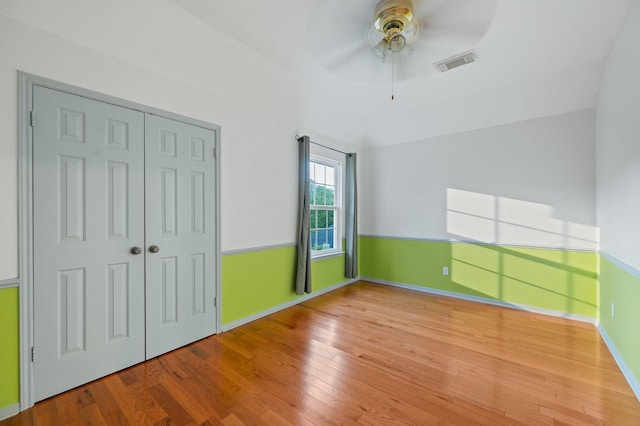 unfurnished bedroom featuring lofted ceiling, a closet, ceiling fan, and hardwood / wood-style flooring