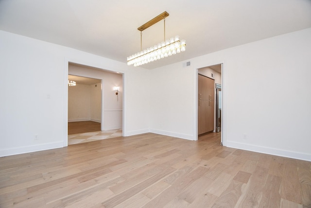 unfurnished room with light hardwood / wood-style floors and a chandelier