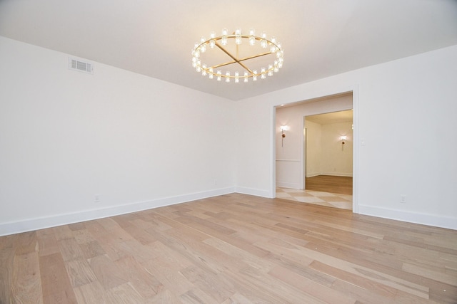 unfurnished room featuring light wood-type flooring and a chandelier