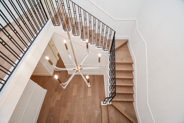 staircase with a chandelier and hardwood / wood-style flooring