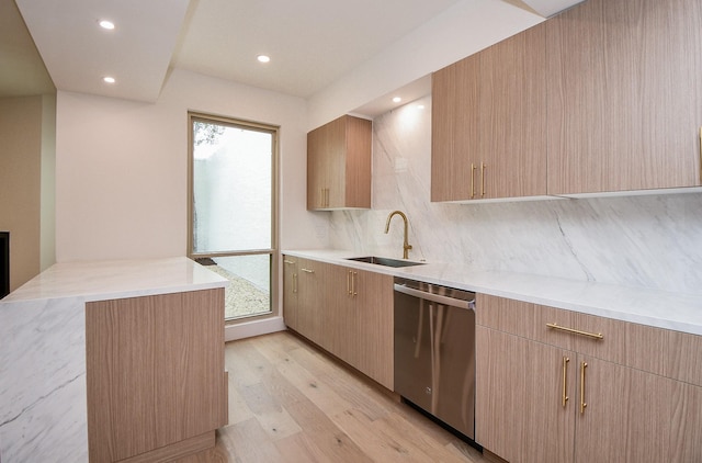 kitchen featuring kitchen peninsula, stainless steel dishwasher, a healthy amount of sunlight, light wood-type flooring, and sink