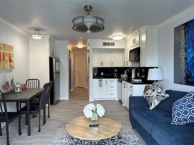 kitchen with white cabinetry, ornamental molding, light hardwood / wood-style floors, backsplash, and appliances with stainless steel finishes