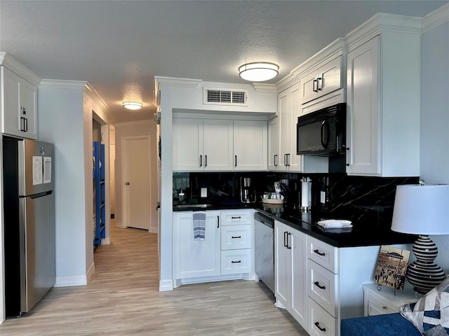 kitchen with light wood-type flooring, appliances with stainless steel finishes, backsplash, and white cabinetry