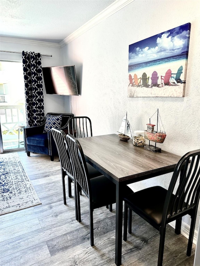 dining area with a textured ceiling, hardwood / wood-style floors, and crown molding