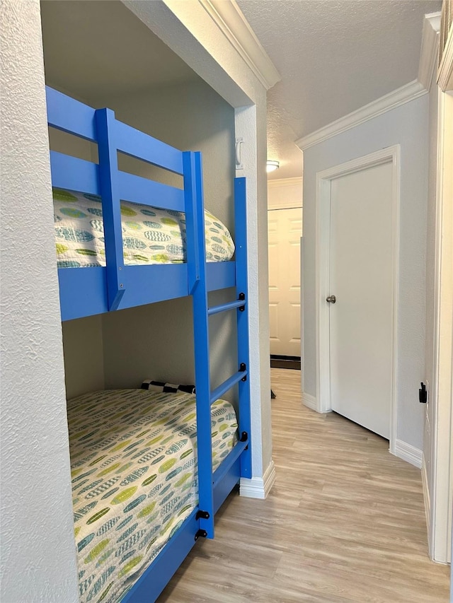 bedroom featuring a textured ceiling, light hardwood / wood-style floors, and crown molding