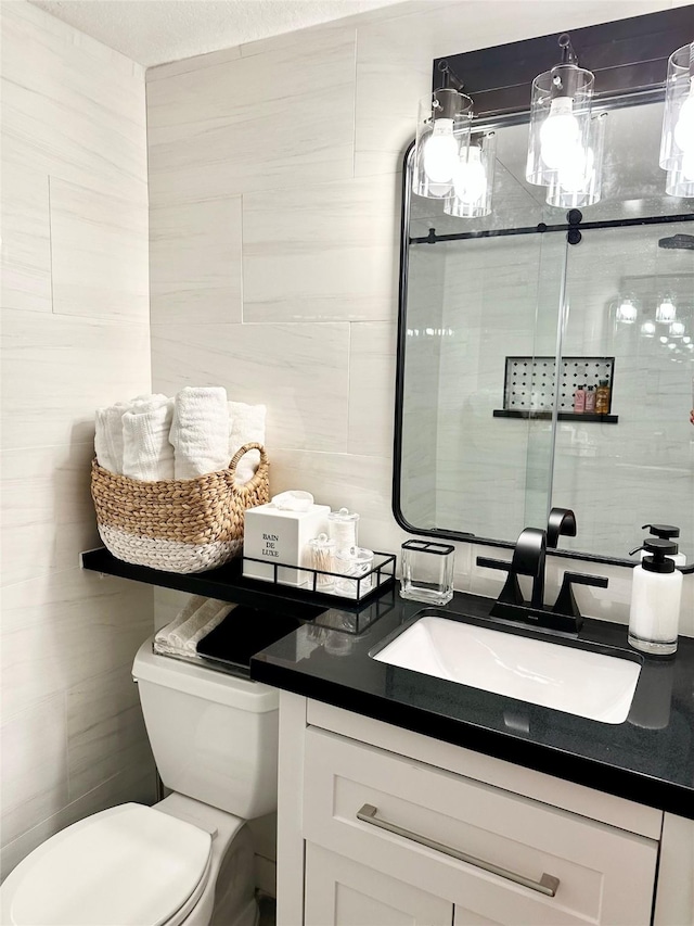 bathroom with toilet, vanity, and tile walls