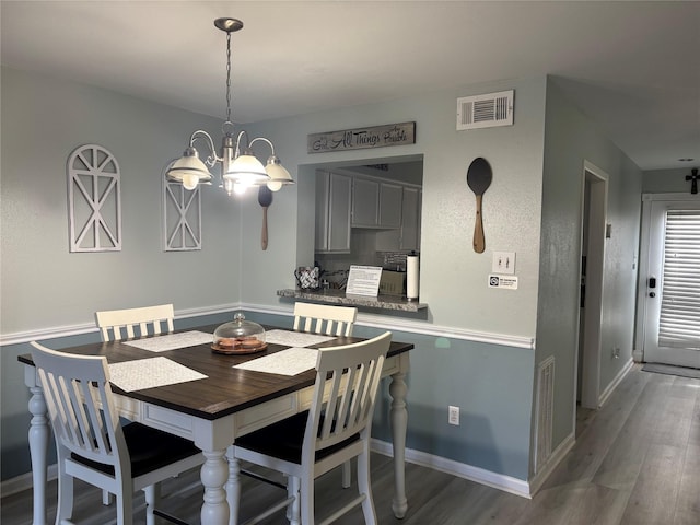 dining area featuring dark hardwood / wood-style flooring and a notable chandelier