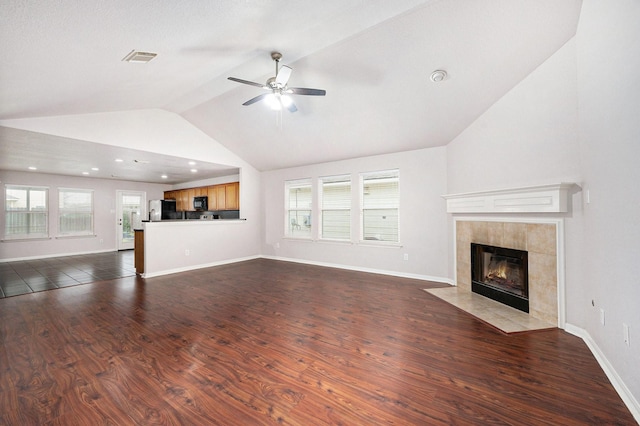 unfurnished living room with vaulted ceiling, a fireplace, ceiling fan, and dark hardwood / wood-style flooring