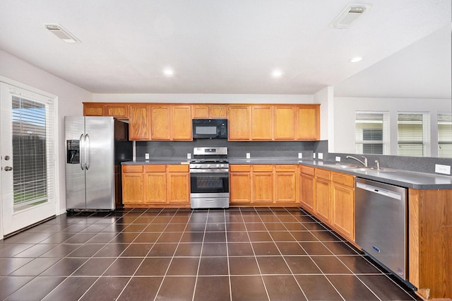 kitchen featuring appliances with stainless steel finishes, kitchen peninsula, dark tile patterned flooring, and sink