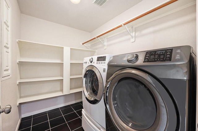 laundry room featuring washer and clothes dryer and dark tile patterned flooring