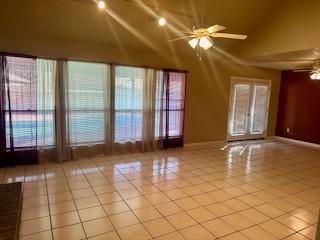 tiled spare room with ceiling fan, lofted ceiling, and plenty of natural light