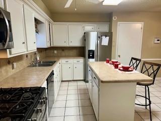 kitchen featuring a kitchen island, white cabinets, stainless steel appliances, and a breakfast bar area