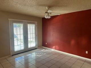 tiled spare room featuring ceiling fan, french doors, and a textured ceiling