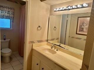 bathroom with toilet, vanity, and tile patterned floors