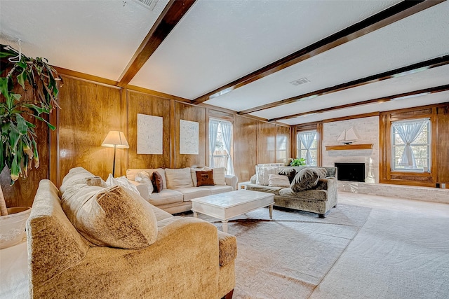 carpeted living room featuring wooden walls, a healthy amount of sunlight, and beamed ceiling