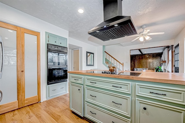 kitchen with black appliances, green cabinetry, island range hood, and a textured ceiling