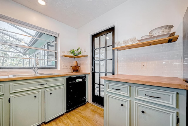 kitchen featuring decorative backsplash, light wood-type flooring, butcher block countertops, black dishwasher, and sink