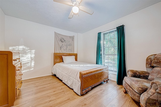 bedroom featuring ceiling fan, light hardwood / wood-style flooring, and multiple windows