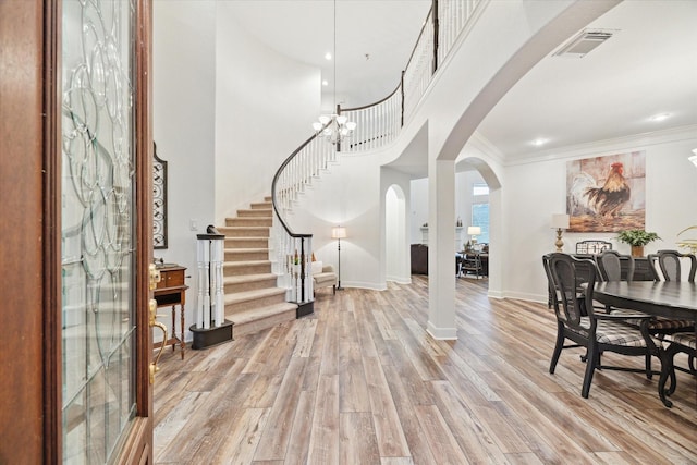 entryway featuring light wood-type flooring, a notable chandelier, and crown molding