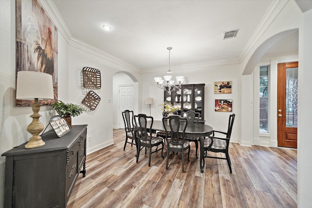 dining space with an inviting chandelier, ornamental molding, and light wood-type flooring