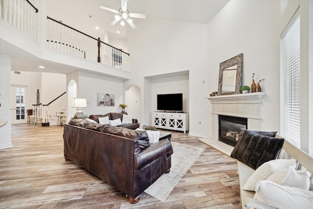 living room with a high ceiling, ceiling fan, and light hardwood / wood-style flooring