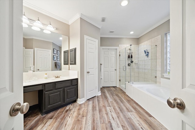 bathroom with plus walk in shower, vanity, crown molding, and hardwood / wood-style floors