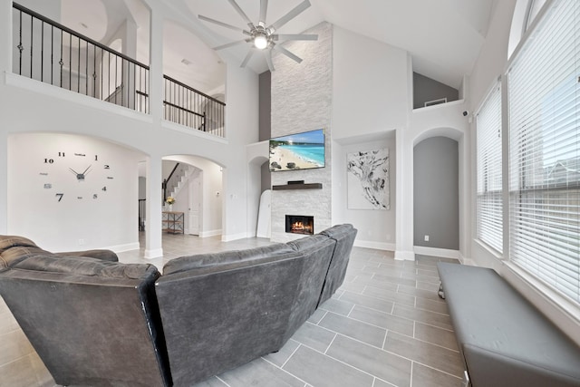 living room featuring ceiling fan, high vaulted ceiling, light tile patterned floors, and a fireplace