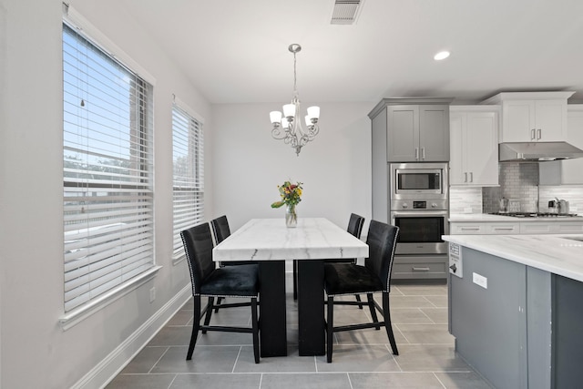 dining space with light tile patterned flooring and a notable chandelier