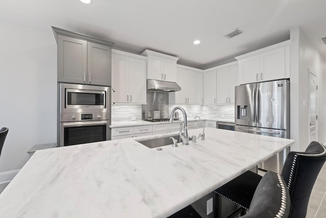 kitchen featuring sink, tasteful backsplash, appliances with stainless steel finishes, a kitchen breakfast bar, and white cabinets