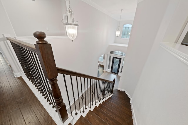 stairway featuring crown molding, hardwood / wood-style floors, and a notable chandelier