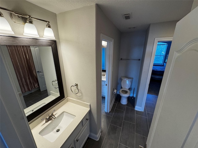 bathroom featuring vanity, toilet, and a textured ceiling