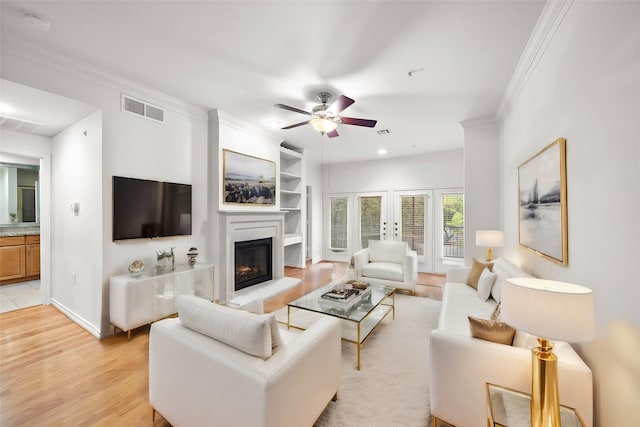 living room with light hardwood / wood-style floors, ceiling fan, and crown molding