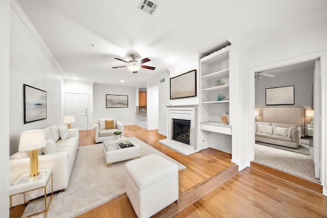 living room with ceiling fan, light hardwood / wood-style floors, and crown molding