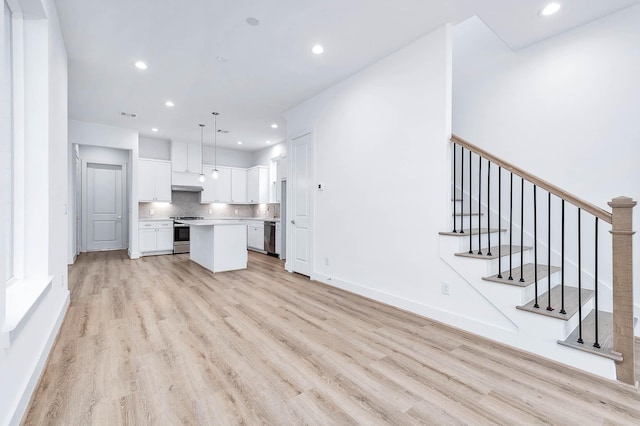 kitchen featuring hanging light fixtures, stainless steel appliances, decorative backsplash, a kitchen island, and white cabinets