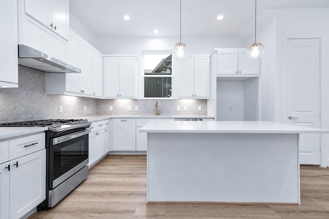 kitchen featuring pendant lighting, a center island, light hardwood / wood-style floors, stainless steel gas stove, and white cabinetry