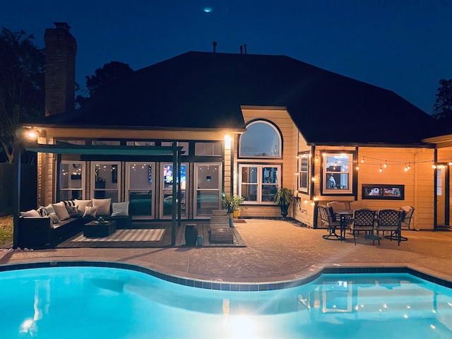 pool at night featuring an outdoor hangout area and a patio area