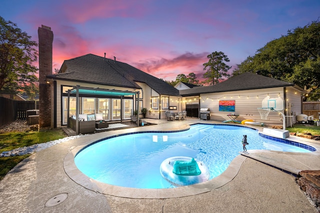 pool at dusk with outdoor lounge area, a patio, and area for grilling