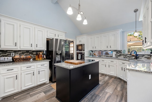 kitchen featuring hanging light fixtures, a center island, black appliances, backsplash, and sink