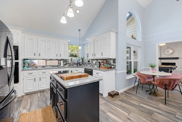 kitchen featuring dishwasher, a center island, decorative light fixtures, high vaulted ceiling, and white cabinetry