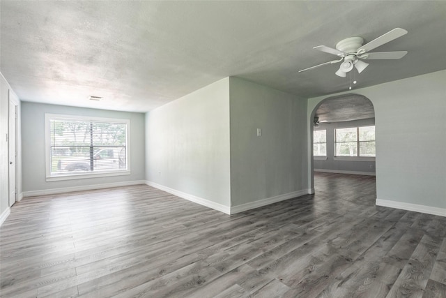 unfurnished room with dark wood-type flooring, a textured ceiling, and ceiling fan