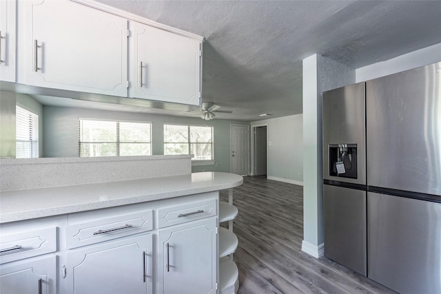 kitchen featuring light wood-type flooring, ceiling fan, stainless steel refrigerator with ice dispenser, and white cabinetry