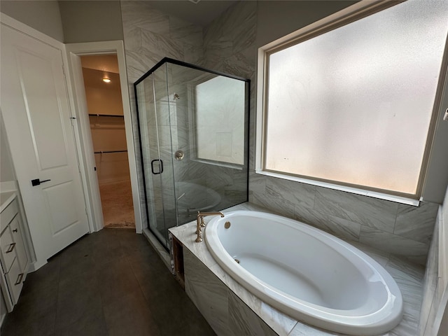 bathroom with a walk in closet, a shower stall, a garden tub, and vanity