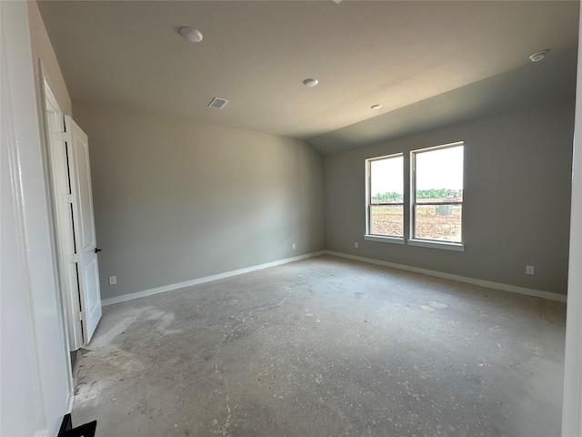 empty room featuring lofted ceiling, visible vents, and baseboards