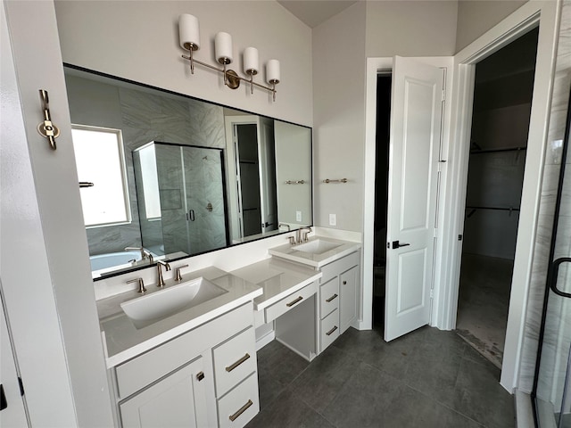 bathroom with a stall shower, double vanity, a sink, and a spacious closet