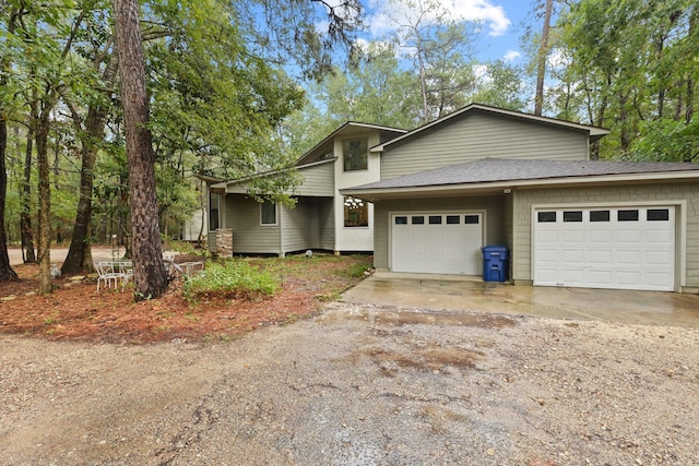 view of front of home with an attached garage, a shingled roof, and dirt driveway