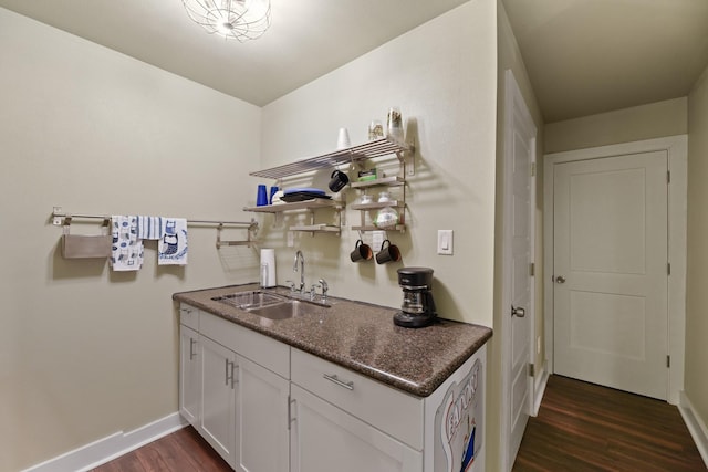 kitchen with white cabinetry, dark wood-type flooring, sink, and dark stone countertops