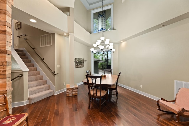 dining space with an inviting chandelier, a towering ceiling, and dark wood-type flooring