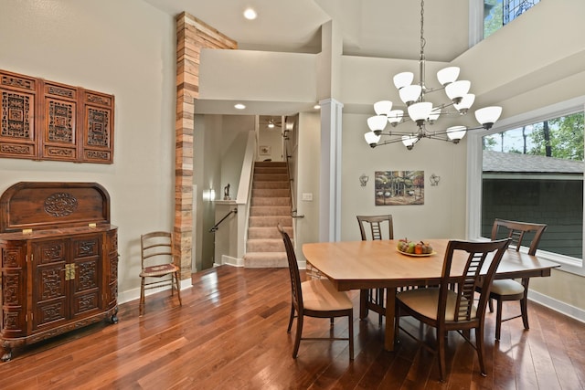 dining space with dark hardwood / wood-style floors, a towering ceiling, and an inviting chandelier