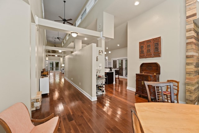 dining room featuring dark wood-type flooring, ceiling fan, and a high ceiling